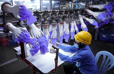 In this Aug. 26, 2020, file photo, a worker inspects disposable gloves at the Top Glove factory in Shah Alam outside Kuala Lumpur, Malaysia. Malaysia's Top Glove Corp., the world's largest rubber glove maker, said in May, 2021, it hopes to swiftly end a U.S. ban on its products due to allegations of forced labor after one of its shipment was seized at a U.S. port. Malaysia's government pledged Monday, July 5, 2021, to take steps to eliminate forced labor after the country was downgraded by the U.S. to the worst level in an annual report on human trafficking.