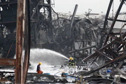 Firefighters spray foam amid twisted metal frames of a charred chemical factory Tuesday, July 6, 2021 in Samut Prakan, Thailand.Firefighters finally extinguished a blaze at a chemical factory just outside the Thai capital early Tuesday, more than 24-hours after it started with an explosion that damaged nearby homes and then let off a clouds of toxic smoke that prompted a widespread evacuation.