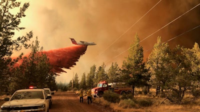 This photo provided by the Oregon Department of Forestry shows a firefighting tanker making a retardant drop over the Grandview Fire near Sisters, Ore., Sunday, July 11, 2021. The wildfire doubled in size to 6.2 square miles (16 square kilometers) Monday, forcing evacuations in the area, while the state's biggest fire continued to burn out of control, with containment not expected until November.