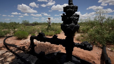 Ashley Williams Watt walks near a wellhead and flowline at her ranch near Crane, Texas, July 9, 2021.