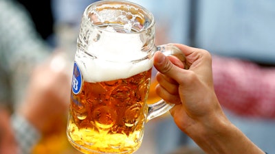 In this Sept. 21, 2019 photo a guest holds glasses of beer during the opening of the 186th 'Oktoberfest' beer festival in Munich, Germany.