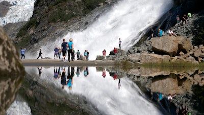 In this July 31, 2013, file photo, tourists visiting the Mendenhall Glacier in the Tongass National Forest are reflected in a pool of water as they make their way to Nugget Falls in Juneau, Alaska. The Biden administration said Thursday, July 15, 2021, that it is ending large-scale, old-growth timber sales on the nation's largest national forest.