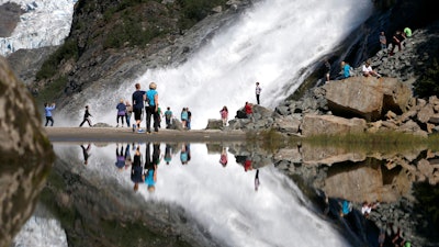 In this July 31, 2013, file photo, tourists visiting the Mendenhall Glacier in the Tongass National Forest are reflected in a pool of water as they make their way to Nugget Falls in Juneau, Alaska. The Biden administration said Thursday, July 15, 2021, that it is ending large-scale, old-growth timber sales on the nation's largest national forest.