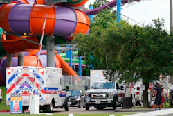 Emergency personnel vehicles are parked near the scene where people are being treated after chemical leak at Six Flags Hurricane Harbor Splashtown.