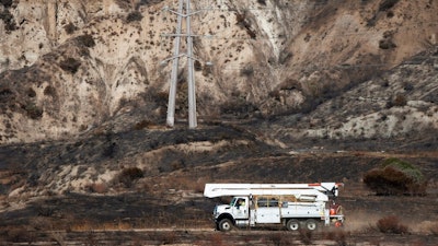 In this Oct. 15, 2019, file photo, SoCal Edison trucks arrive at the site of a transformer tower in Sylmar, Calif., suspected of being responsible for starting the Saddleridge Fire. Pacific Gas & Electric plans to bury 10,000 miles of its power lines in an effort to prevent its fraying grid from sparking wildfires when electrical equipment collides with millions of trees and other vegetation sprawling across its drought-stricken service.