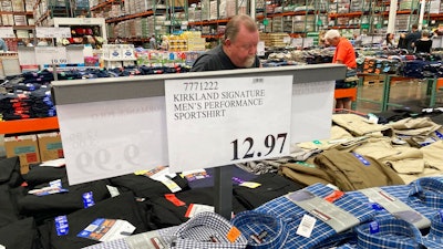 A sign displays the price for shirts as a shopper peruses the offerings at a Costco warehouse on Thursday, June 17, 2021, in Lone Tree, Colo. American consumers faced a third straight monthly surge in princes in June, the latest sign that a rapid reopening of the economy is fueling a pent-up demand for goods and services that in many cases remain in short supply.