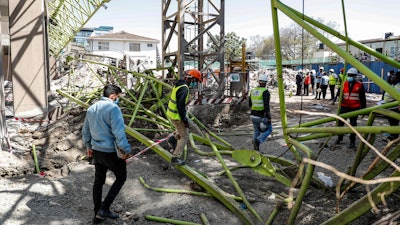 Construction workers observe the wreckage after a crane collapsed at a construction project to build a 14-storey student hostel in Nairobi, Kenya Thursday, Aug. 26, 2021. Police in Kenya's capital say nine people are dead, including two Chinese engineers, after the crane collapsed at the site being supervised by a Chinese construction firm.