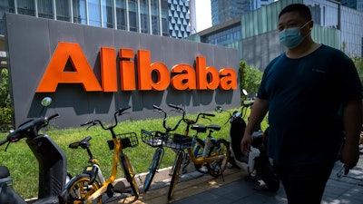 A man wearing a face mask walks past the offices of Chinese e-commerce firm Alibaba in Beijing, Tuesday, Aug. 10, 2021. China's largest e-commerce company, Alibaba, says it has fired a manager accused of sexually assaulting a female employee during a business trip.