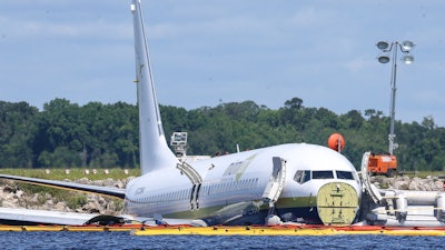 In this May 4, 2019, file photo, a charter plane carrying 143 people and traveling from Cuba to north Florida sits in a river at the end of a runway in Jacksonville, Fla. Investigators say the loss of braking power on a rain-soaked flooded runway caused a cargo plane chartered by the Pentagon to slide into a Florida river in 2019, the National Transportation Safety Board said Wednesday, AUg. 4, 2021.