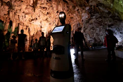 Persephone guides the visitors inside Alistrati cave, about 135 kilometers (84 miles) northeast of Thessaloniki, Greece, Monday, Aug. 2, 2021. Persephone, billed as the world's first robot used as a tour guide inside a cave, has been welcoming visitors to the Alistrati cave, since mid-July.