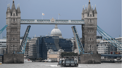 A boat sails down the River Thames in London, Monday Aug. 9, 2021 in front of Tower Bridge that is stuck in the fully open position due to a technical fault.