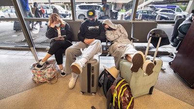 Stranded travelers sleep on the seats of the ticketing waiting area, Tuesday, Aug. 3, 2021. at Philadelphia International Airport in Philadelphia.