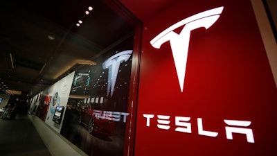 This Feb. 9, 2019, file photo shows a sign bearing the company logo outside a Tesla store in Cherry Creek Mall in Denver. A Tesla using its partially automated driving system slammed into a Florida Highway Patrol cruiser Saturday, Aug. 28, 2021 on an interstate near downtown Orlando and narrowly missed its driver, who had pulled over to assist a disabled vehicle.