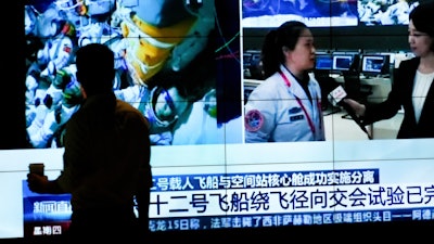 A man watches a TV screen showing CCTV broadcasting Chinese astronauts inside the Shenzhou-12 manned spacecraft, Beijing, Sept. 16, 2021.