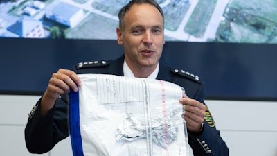 Police spokesman Thomas Geithner shows the remains of the metal foil of a balloon during a press conference in Dresden, Germany, Tuesday, Sept 14, 2021 discovered in the substation Dresden-Sued (Dresden-South).
