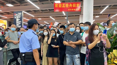 Police stand guard as supporters of Huawei CFO Meng Wanzhou gather at Shenzhen Bao'an International Airport in Shenzhen in southern China's Guangdong Province, Saturday, Sept. 25, 2021. China's government was eagerly anticipating the return of a top executive from global communications giant Huawei Technologies on Saturday following what amounted to a high-stakes prisoner swap with Canada and the U.S.