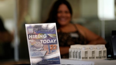 A hiring sign is placed at a booth for prospective employers during a job fair Wednesday, Sept. 22, 2021, in the West Hollywood section of Los Angeles. The number of Americans applying for unemployment aid rose last week for a second straight week to 351,000, a sign that the delta variant of the coronavirus may be disrupting the job market’s recovery, at least temporarily.