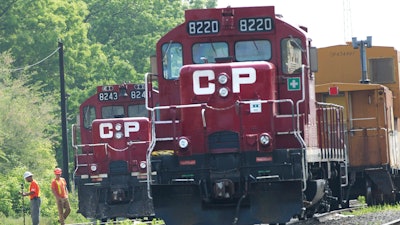 In this May 23, 2012, file photo, surveyors work next to Canadian Pacific Rail trains which are parked on the train tracks in Toronto. A planned shareholder vote on Canadian National's $33.6 billion offer has been delayed, Wednesday, Sept. 1, 2021, after regulators rejected a key part of the plan, so now Kansas City Southern can consider all of its options, including a competing $31 billion offer from Canadian Pacific Railway.