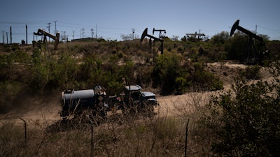 A truck drives past pump jacks operating at the Inglewood Oil Field, Thursday, June 10, 2021, in Los Angeles.