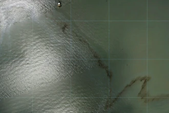 Photos captured by National Oceanic and Atmospheric Administration aircraft Tuesday, Aug. 31, 2021 and reviewed by The Associated Press show a miles long black slick floating in the Gulf of Mexico near a large rig marked with the name Enterprise Offshore Drilling.