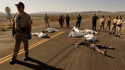 In this May 11, 2003, file photo, protesters lie on the pavement opposed to the proposed Yucca Mountain nuclear storage facility and weapons testing after crossing the line into the Nevada Test Site at Mercury, Nev., and were arrested for trespassing about 70 miles north of Las Vegas. A bipartisan group of lawmakers is renewing the push to expand a federal compensation program for radiation exposure following uranium mining and nuclear testing carried out during the Cold War.