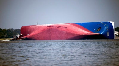 In this Sept. 9, 2019, file photo, a Moran tugboat nears the stern of the capsizing vessel Golden Ray near St. Simons Sound off the coast of Georgia.