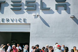 Tesla owners, Tesla employees and local political leaders gather at the service bay doors during an event on Sept. 9, 2021, to celebrate a partnership between Tesla and the Nambé Pueblo after the electric car company repurposed a defunct casino into a sales, service and delivery center near Santa Fe, N.M.