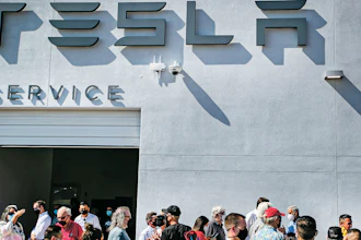 Tesla owners, Tesla employees and local political leaders gather at the service bay doors during an event on Sept. 9, 2021, to celebrate a partnership between Tesla and the Nambé Pueblo after the electric car company repurposed a defunct casino into a sales, service and delivery center near Santa Fe, N.M.