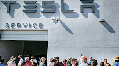 Tesla owners, Tesla employees and local political leaders gather at the service bay doors during an event on Sept. 9, 2021, to celebrate a partnership between Tesla and the Nambé Pueblo after the electric car company repurposed a defunct casino into a sales, service and delivery center near Santa Fe, N.M.