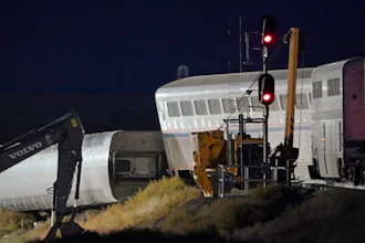 Cars from an Amtrak train that derailed the day before are shown illuminated by floodlights, late Sunday, Sept. 26, 2021, as they rest near a train signal near Joplin, Mont. The westbound Empire Builder was en route to Seattle from Chicago with two locomotives and 10 cars.