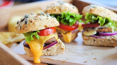 Several small cheeseburger sliders made from worm burger patties. The insect burgers are made from buffalo worms, which are the larvae of the darkling beetle.