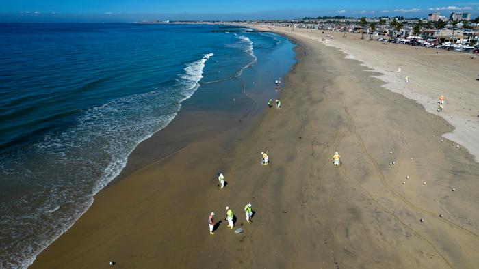 Workers clean oil from the sand south of the pier in Newport Beach, Calif., Tuesday, Oct. 5, 2021. A leak in an oil pipeline caused a spill off the coast of Southern California, sending about 126,000 gallons of oil into the ocean, some ending up on beaches in Orange County.