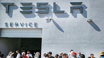Tesla owners, Tesla employees and local political leaders gather at the service bay doors during an event on Sept. 9, 2021, to celebrate a partnership between Tesla and the Nambé Pueblo after the electric car company repurposed a defunct casino into a sales, service and delivery center near Santa Fe, N.M. Tesla has opened a store on tribal land in New Mexico, sidestepping car dealership laws that prohibit car companies from selling directly to customers.