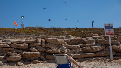 A woman looks at drones carrying goods as part of the National Drone Initiative test, Tel Aviv, Oct. 11, 2021.