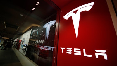 This Feb. 9, 2019, file photo shows a sign bearing the company logo outside a Tesla store in Cherry Creek Mall in Denver. A driver was behind the wheel when a Tesla electric car crashed and burned last April in Houston, killing two men, neither of whom was found in the driver’s seat. The U.S. National Transportation Safety Board announced the findings in an investigative report released Thursday, Oct. 21, 2021 on the April 17 crash on a residential road in Spring, Texas.