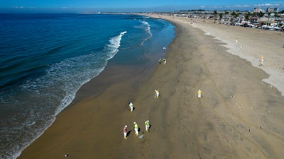 Workers clean oil from the sand south of the pier in Newport Beach, Calif., Tuesday, Oct. 5, 2021. A leak in an oil pipeline caused a spill off the coast of Southern California, sending about 126,000 gallons of oil into the ocean, some ending up on beaches in Orange County.