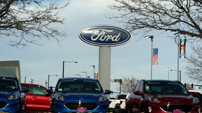 In this Sunday, April 25, 2021, photograph, the blue oval logo of Ford Motor Company is shown over a row of unsold 2021 Escapes at a dealership in east Denver. The global computer chip shortage cut into third-quarter profits at both Ford and crosstown rival General Motors, with both companies having to temporarily close factories, pinching supplies on dealer lots, according to results announced Wednesday, Oct. 27.