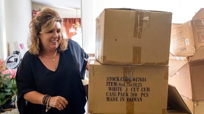 Ginger Pigg moves boxes of shopping bags in the storage room of her gift boutique The Perfect Pigg in Cumming, Ga. on Thursday afternoon, Oct. 22, 2021. The bags should have been delivered in four weeks, but took 14 weeks.