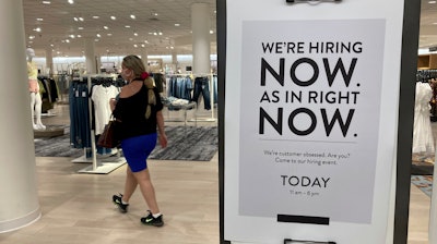 In this May 21, 2021 file photo, a customer walks behind a sign at a Nordstrom store seeking employees in Coral Gables, Fla. On Friday, Oct. 8, U.S. employers added just 194,000 jobs in September, a second straight tepid gain and evidence that the pandemic still has a grip on the economy with many companies struggling to fill millions of open jobs.