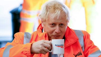 Britain's Prime Minister Boris Johnson holds a mug, during a visit to a construction site in Manchester, England, Monday, Oct. 4, 2021.