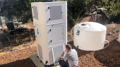 Ted Bowman, design engineer with Tsunami Products, installs a unit in homeowner Don Johnson's backyard in Benicia, Calif., Sept. 28, 2021. The recent invention can make water out of the air and in parched California, some homeowners are already buying the pricey devices. The air-to-water systems work like air conditioners by using coils to chill air, then collect water drops in a basin.