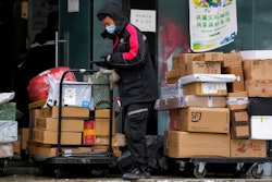 A worker of a private delivery company, wearing a face mask, sorts out parcels at its distribution center in Beijing on Nov. 7, 2021.