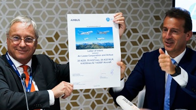 Airbus chief commercial officer Christian Scherer, left, and Airbus CEO Guillaume Faury react after signing a commemorative paper marking a deal at the Dubai Air Show in Dubai, United Arab Emirates, Monday, Nov. 15, 2021.