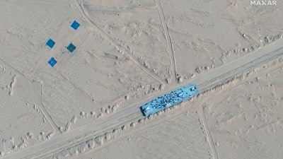 This satellite image provided by Maxar Technologies shows a building on rail tracks in Ruoqiang county, China, Wednesday, Oct. 20, 2021. Satellite images appear to show China has built mock-ups of U.S. Navy aircraft carriers and destroyers in its northwestern desert.