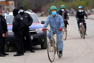 Vietnamese workers who are helping construct the first Chinese car tire factory in Europe ride bicycles past security officers near the northern Serbian town of Zrenjanin, 50 kilometers north of Belgrade, Serbia, Thursday, Nov. 18, 2021.