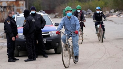 Vietnamese workers who are helping construct the first Chinese car tire factory in Europe ride bicycles past security officers near the northern Serbian town of Zrenjanin, 50 kilometers north of Belgrade, Serbia, Thursday, Nov. 18, 2021.