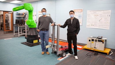 UC engineering students Sam King, left, and Yufeng Sun stand next to the autonomous robot they are building. Sun developed a successful AI that could find and open doors. Now he is translating his simulation to real-world hardware.