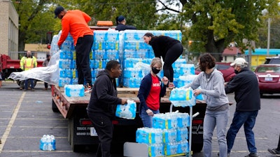Volunteers prepare bottled water to be distributed to residents at the local high school parking lot Thursday, Oct. 21, 2021, in Benton Harbor, Mich. The water system in Benton Harbor has tested for elevated levels of lead for three consecutive years. In response, residents have been told to drink and cook with bottled water and the state has promised to spend millions replacing lead service lines.