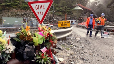 Workers walks past a bouquet of flowers for victims of mine explosion at the Pike River mine at Greymouth, New Zealand on June 28, 2011.