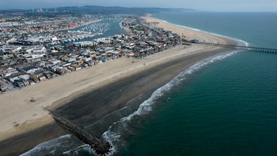 An aerial photo shows the closed beach after oil washed up on a beach in Newport Beach, Calif., on Oct. 6, 2021. A month after an offshore oil spill, environmental advocates say they plan to sue the federal government over the failure to review and update plans for platforms off the Southern California coast.